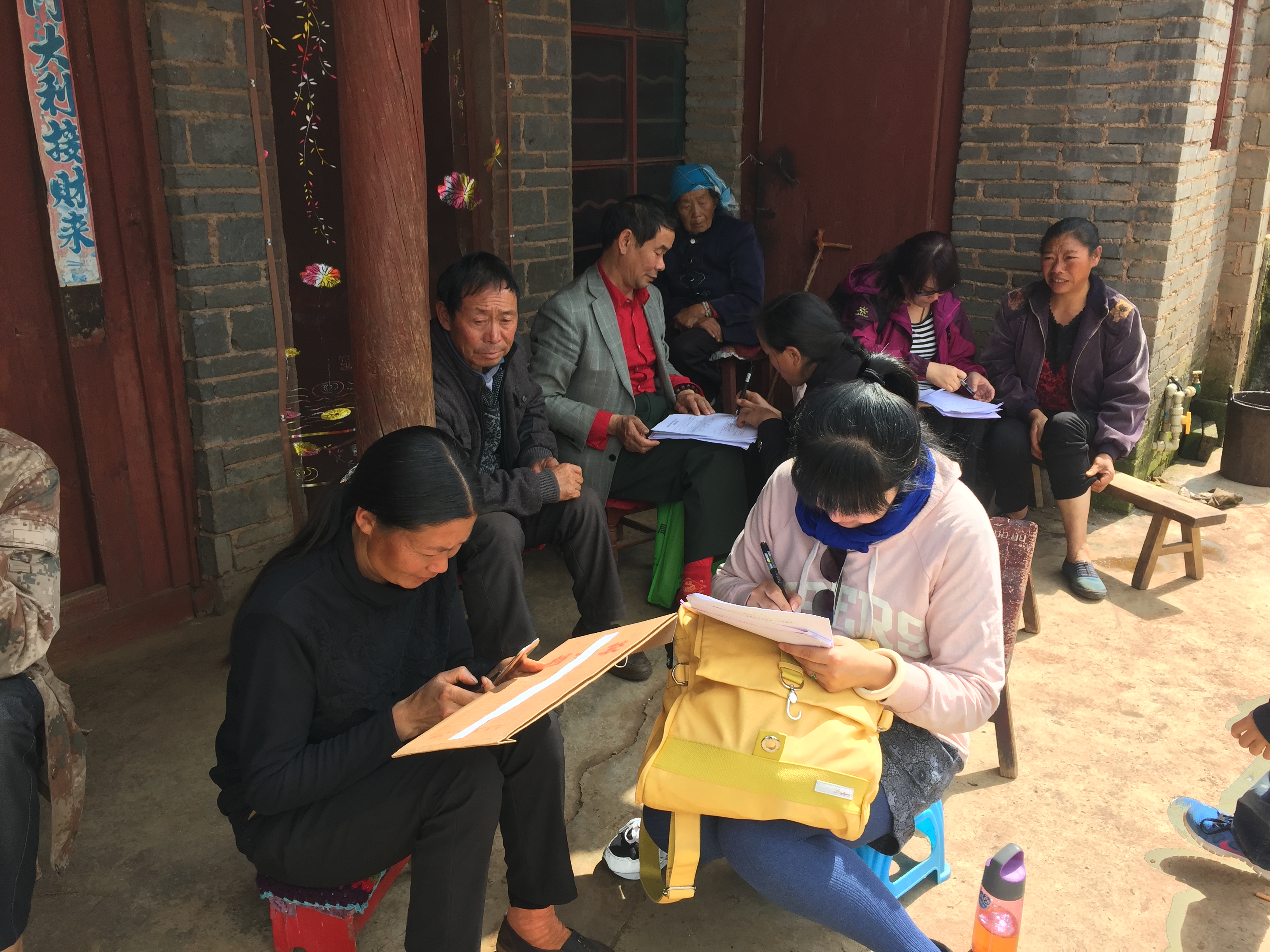 图为教职工认真同贫困户交流并填写问卷